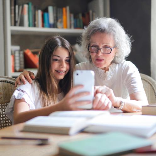 Oma en kleindochter kijken samen op een smartphone.